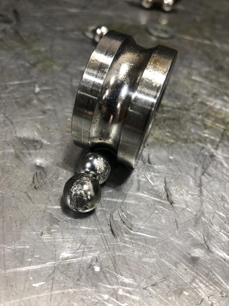 Beschädigte Lagerlaufbahn und Lagerkugeln auf dem Werkstatttisch bei MaiGears